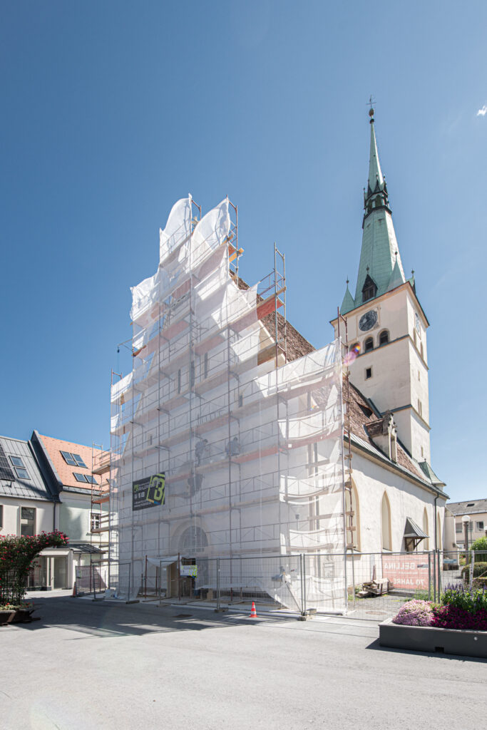 Kirche in Voitsberg während der Fassadensanierung mit Gerüst und Schutznetz