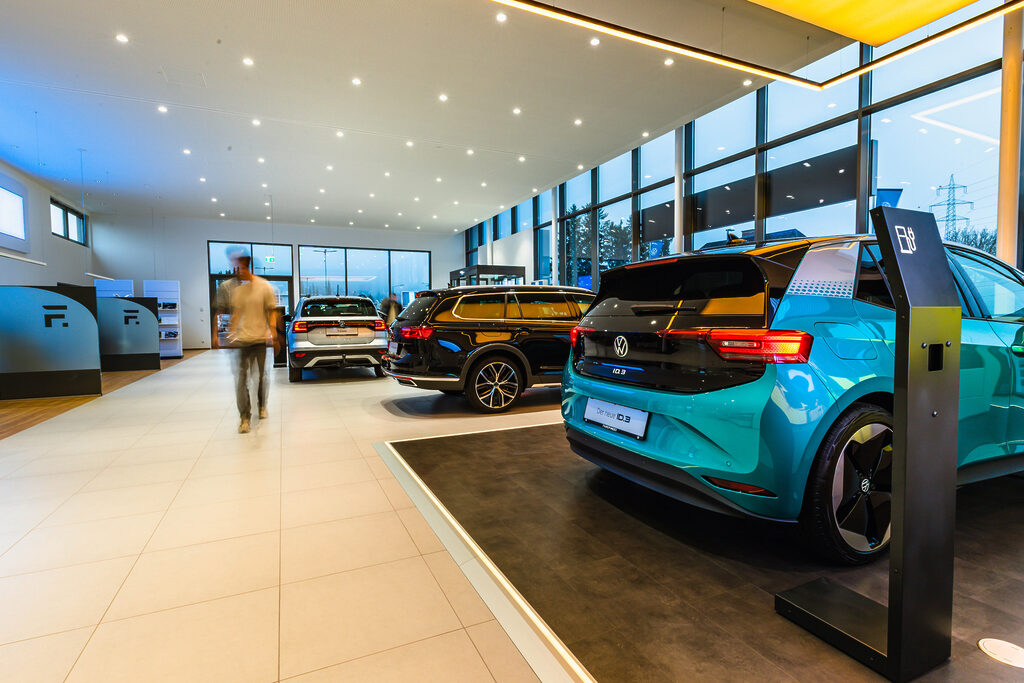 Verkaufsraum Autohaus Fripertinger - sehr heller, ordentlicher Raum mit mehreren Autos, eine Person ist verschwommen zu sehen