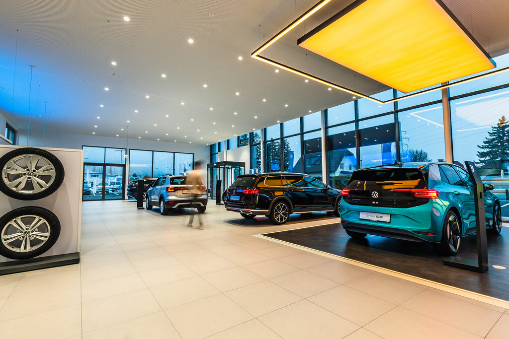 Verkaufsraum Autohaus Fripertinger - sehr heller, ordentlicher Raum mit mehreren Autos, eine Person ist verschwommen zu sehen