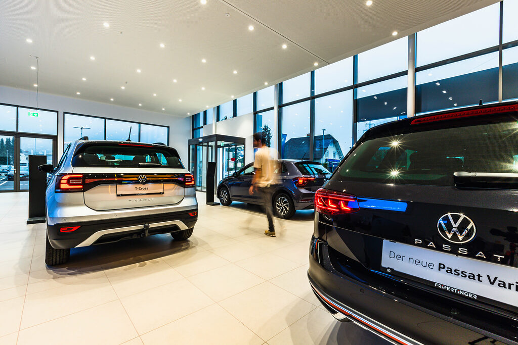 Verkaufsraum Autohaus Fripertinger - sehr heller, ordentlicher Raum mit mehreren Autos, eine Person ist verschwommen zu sehen
