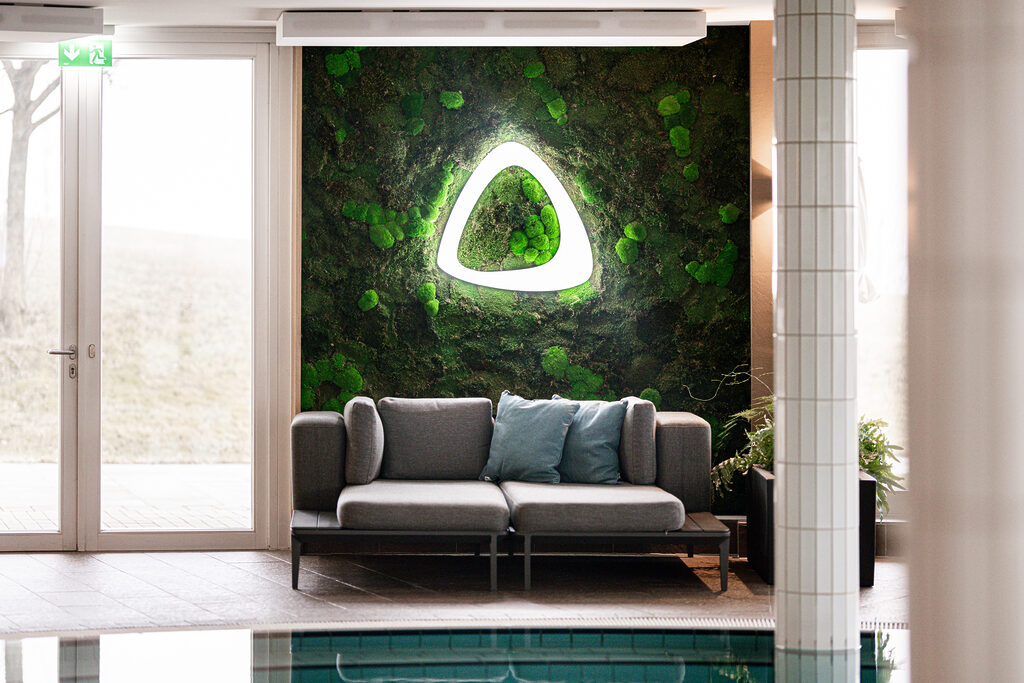 Aufnahme eines Spa der Therme Nova - zusehen ist eine Mooswand, davor eine Liegemöglichkeit, auf der Mooswand ist das Logo der Therme zusehen